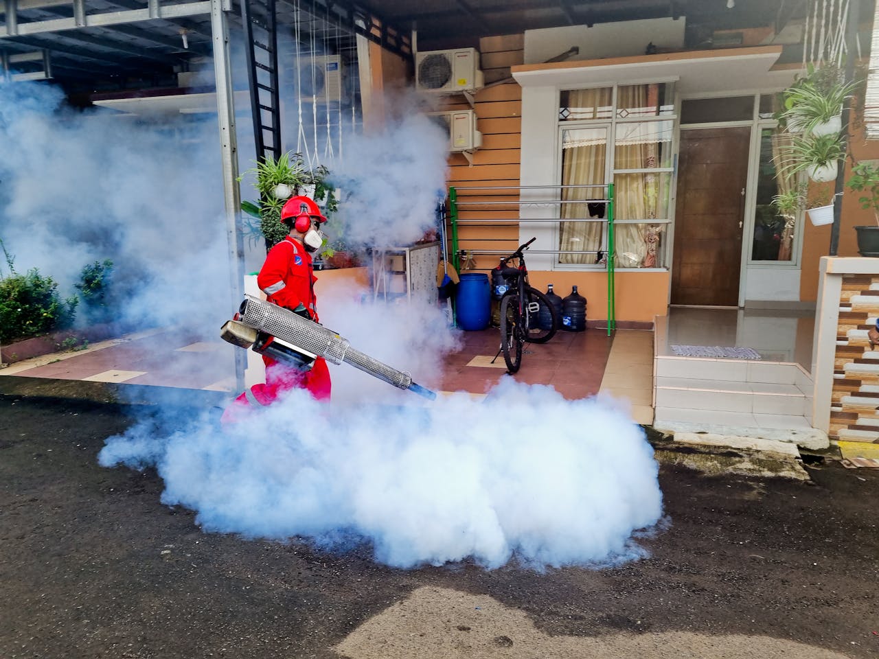services-02 Pest control specialist using a smoke machine to fumigate outside a house.